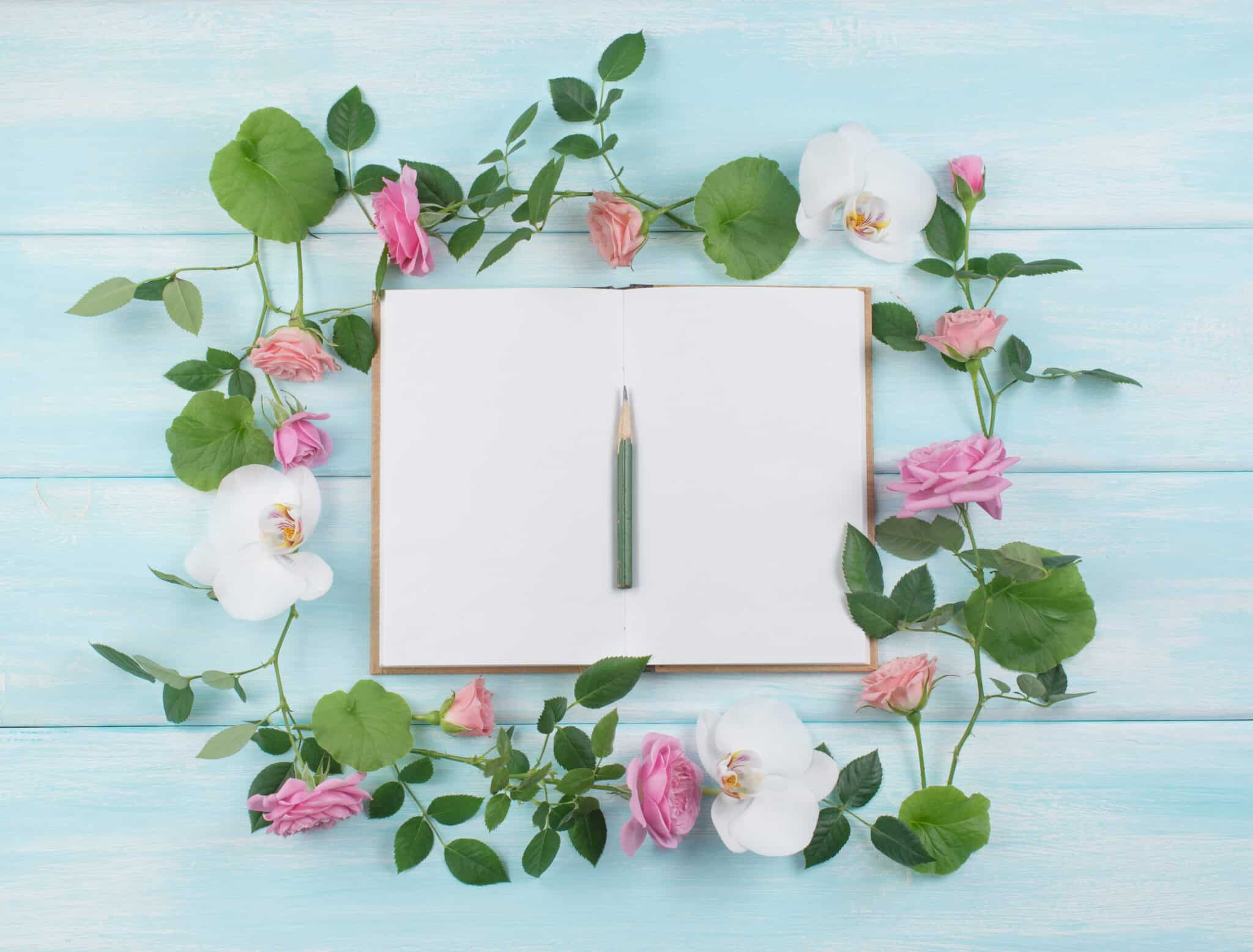 Floral frame consists of roses and orchid flowers and notebook
