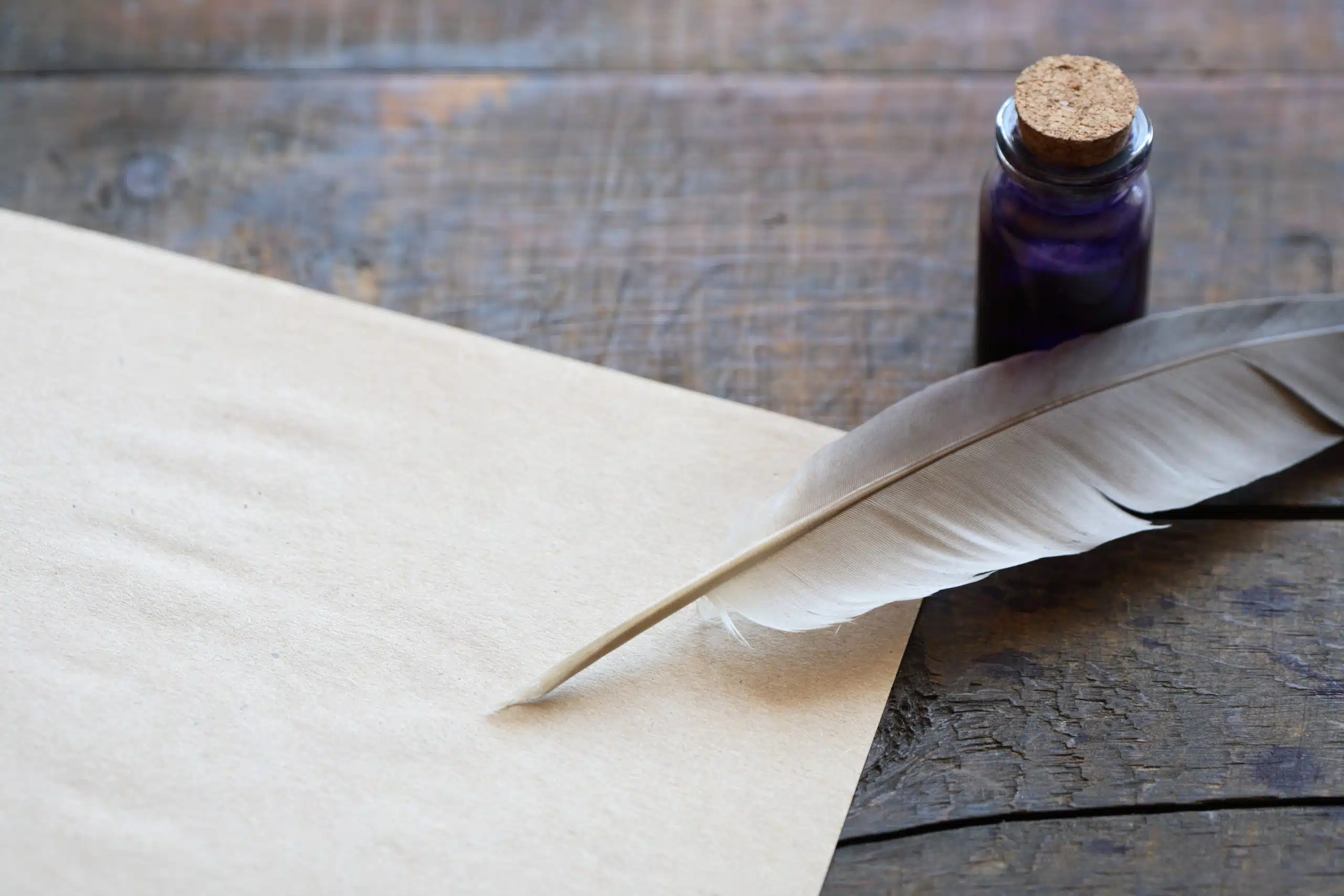 Scroll, quill, and inkwell on wooden desk
