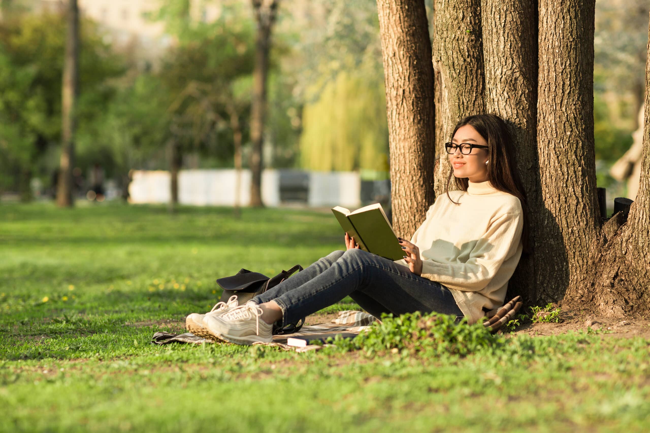 Girl reading a book sitting under the tree in park
