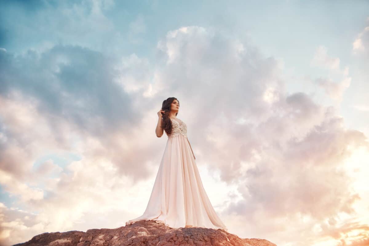 Gorgeous brunette lady in the mountains at sunset and blue sky with clouds