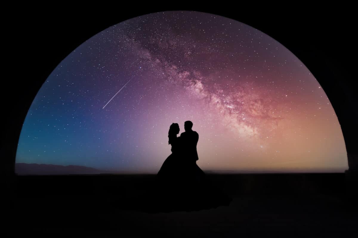 silhouette of a loving couple standing under the big dome of the galactic sky