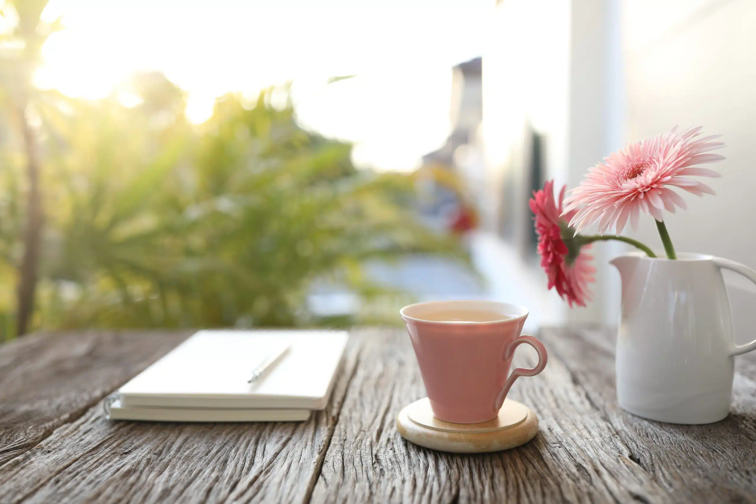 Pink cup and gerbera flowers and notebook
