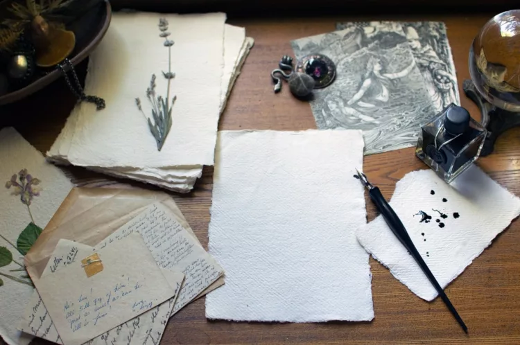 Desk with vintage papers, inkwell, pen, and pressed flowers