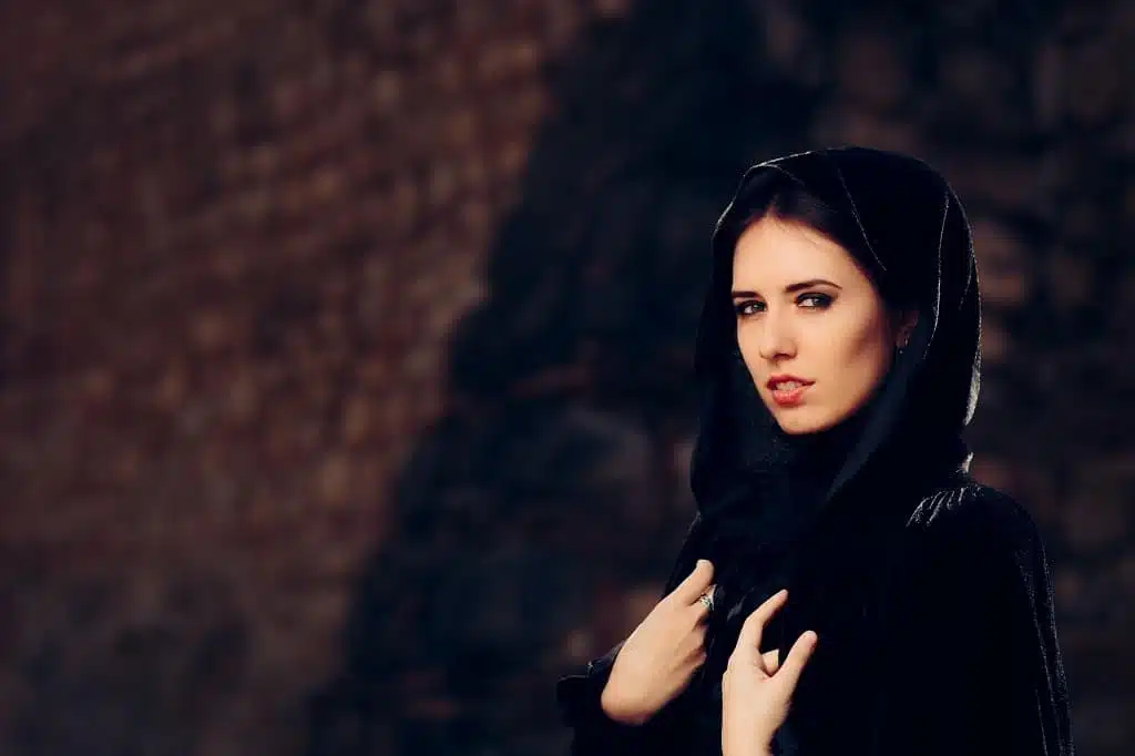 Beautiful dark princess in dark hooded cape looking fierce and mysterious.