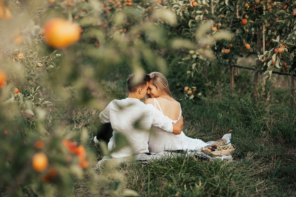 Loving vintage couple enjoying picnic in apples orchard.