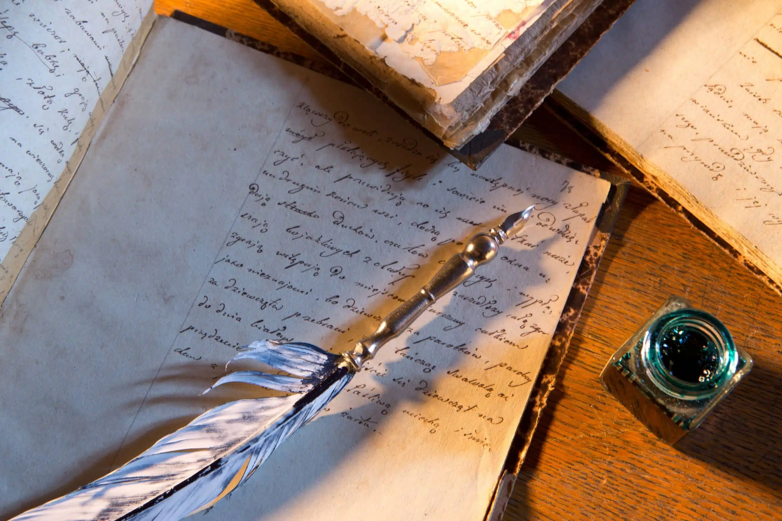 Quill pen on vintage notebook with medieval writing