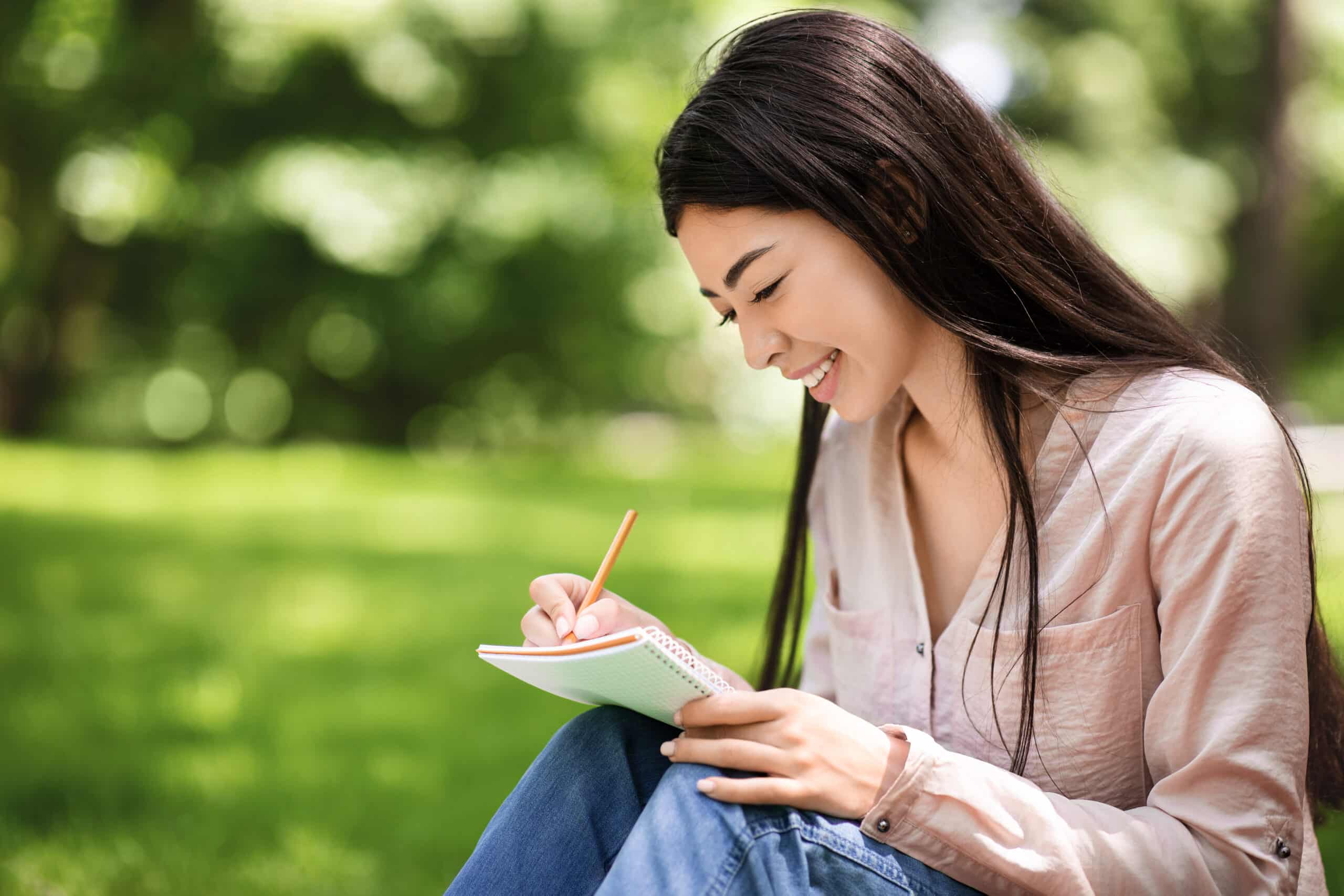 Young Asian girl writing outdoor in the park.