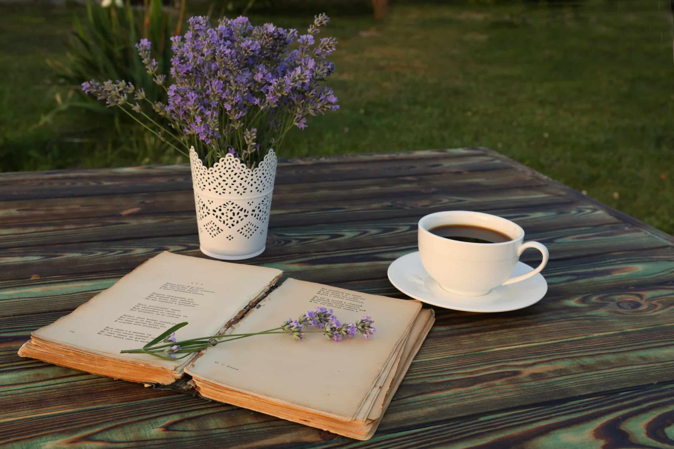 cup of coffee and poetry book on wooden table with lavender flowers