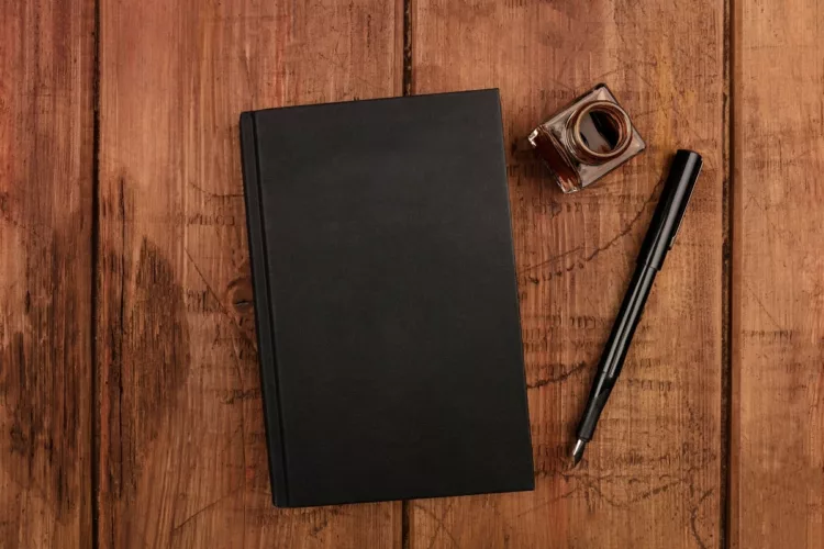 black covered journal with vintage pen and inkpot