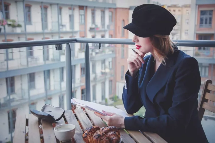 Beautiful young woman elegantly dressed with a hat have a coffee break while writing