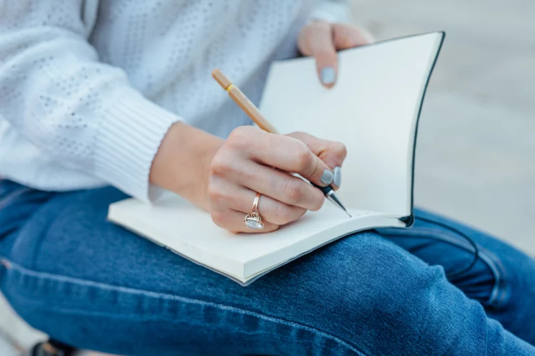 female hand writing in her notebook outdoor