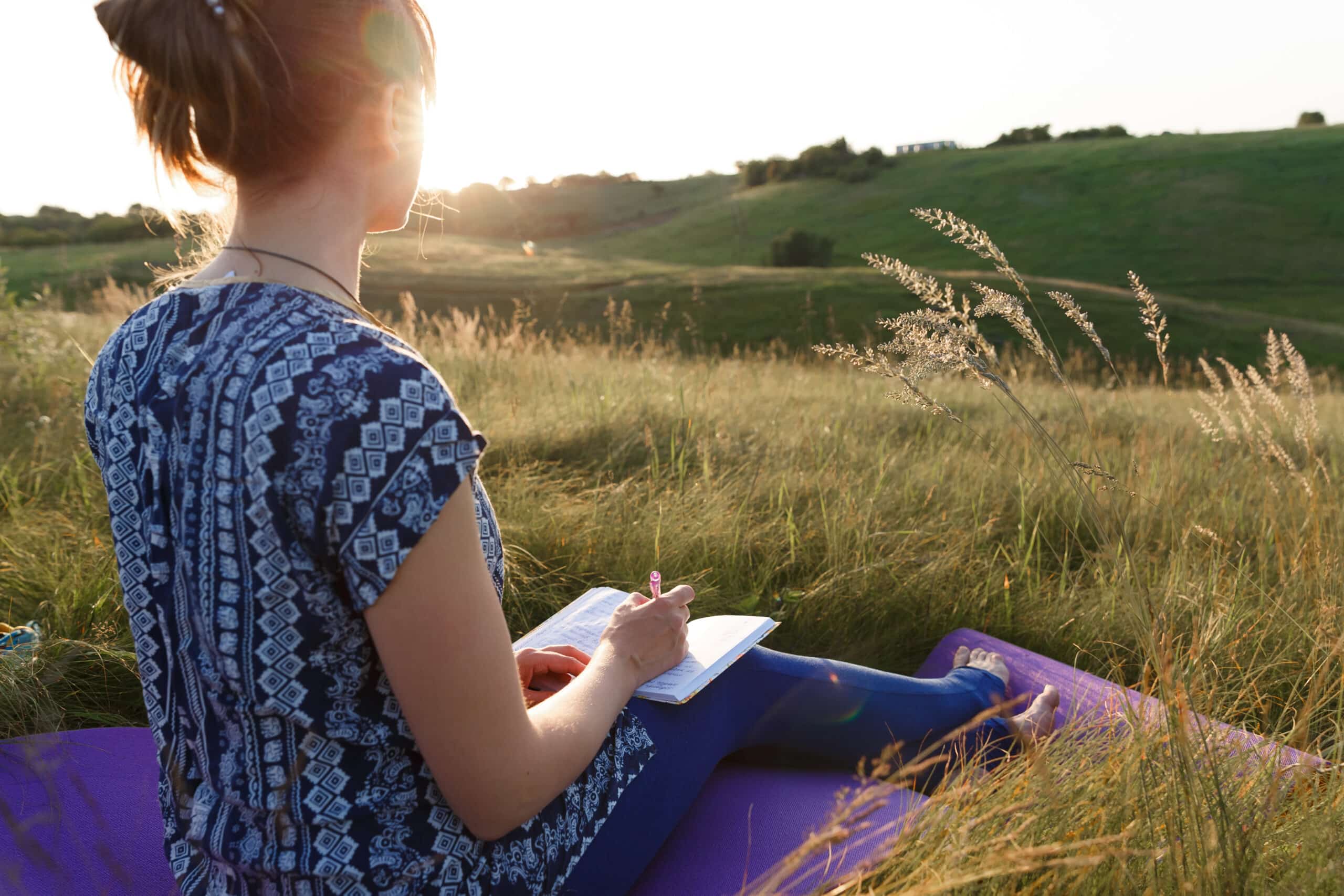 woman reflective writing outdoors in the field