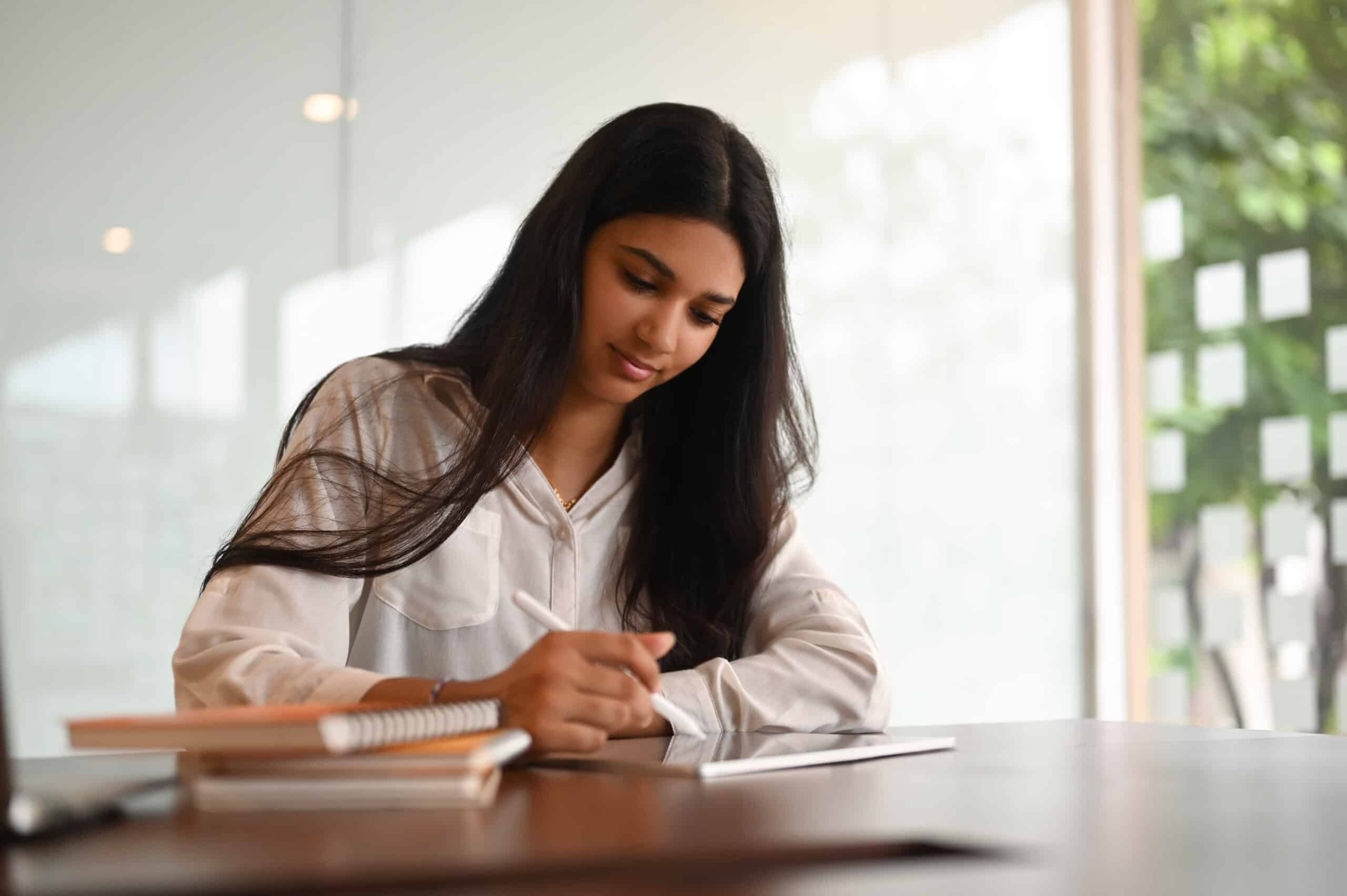 young attractive indian woman writing in her notebook