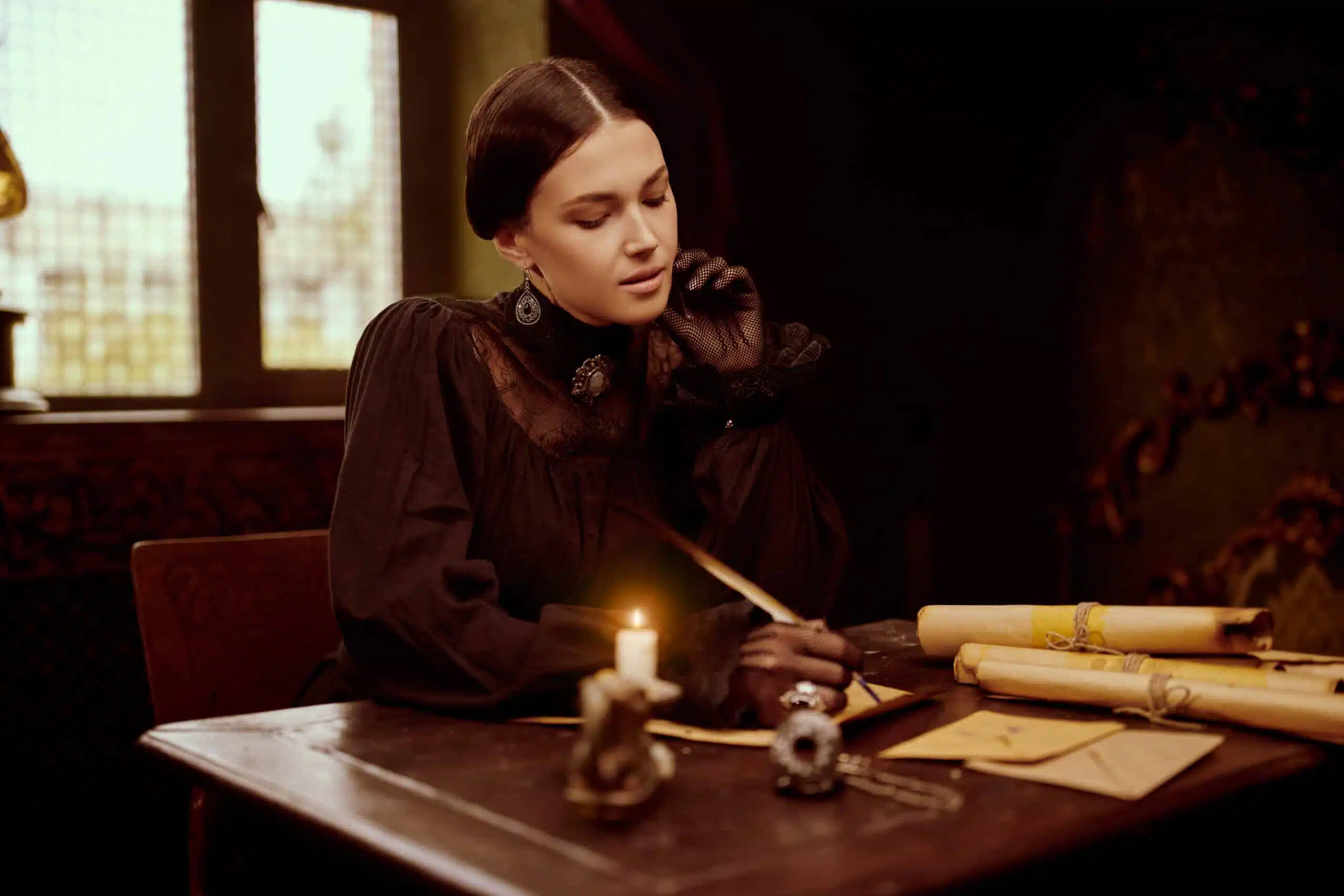 retro woman writing at her desk in a dark room with lit candle