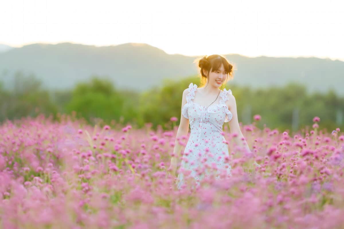 pretty lady dressed in white dress walking in pink flowers garden