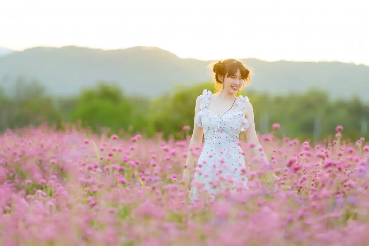 pretty lady dressed in white dress walking in pink flowers garden