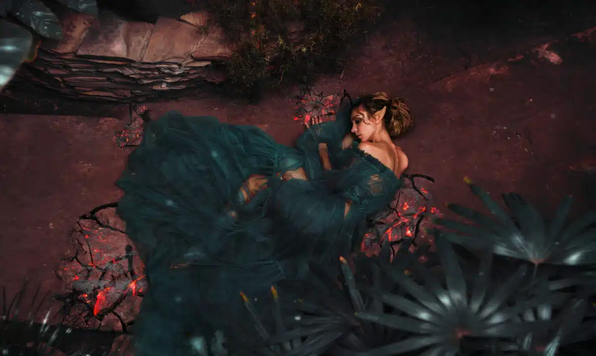 The girl elf in a chic dress lies on the floor among the flowers