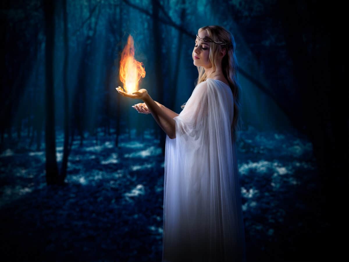 Elven girl with fire in night forest