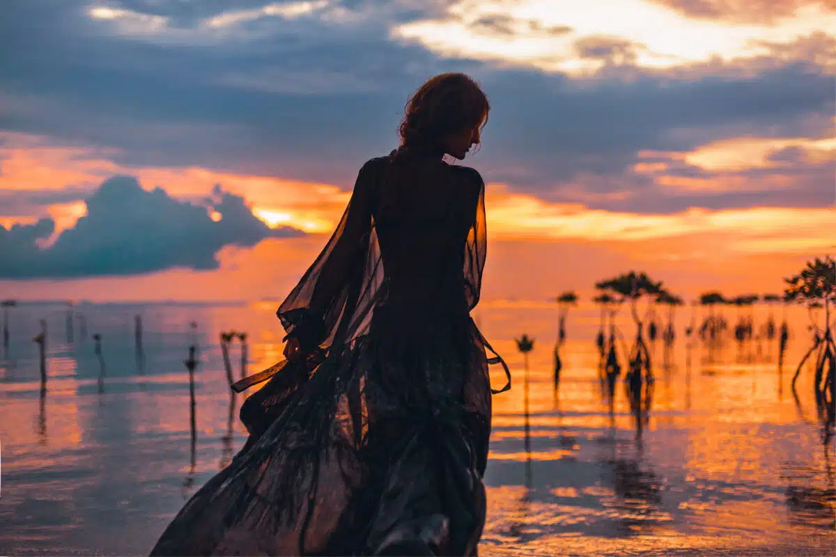 young woman standing in water at sunset silhouette