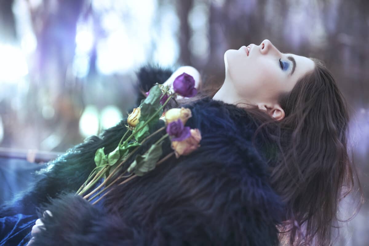 a beautiful mysterious lady in black lying in the forest with flowers