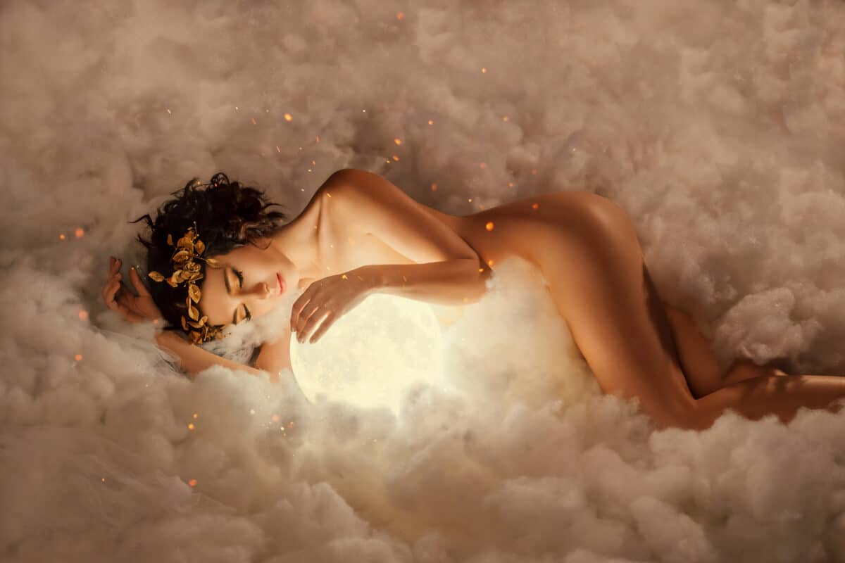 the night and day goddess sleeps in the clouds, as in a thick white fog, hugs the full moon, a naked nude sexy girl with a golden wreath and makeup, with childish innocent face in the glare of fire