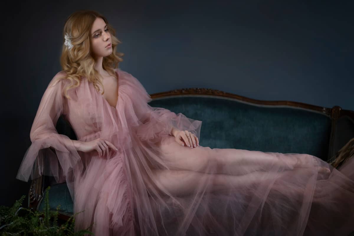 sad aristocratic lady in a pink dress on an antique sofa