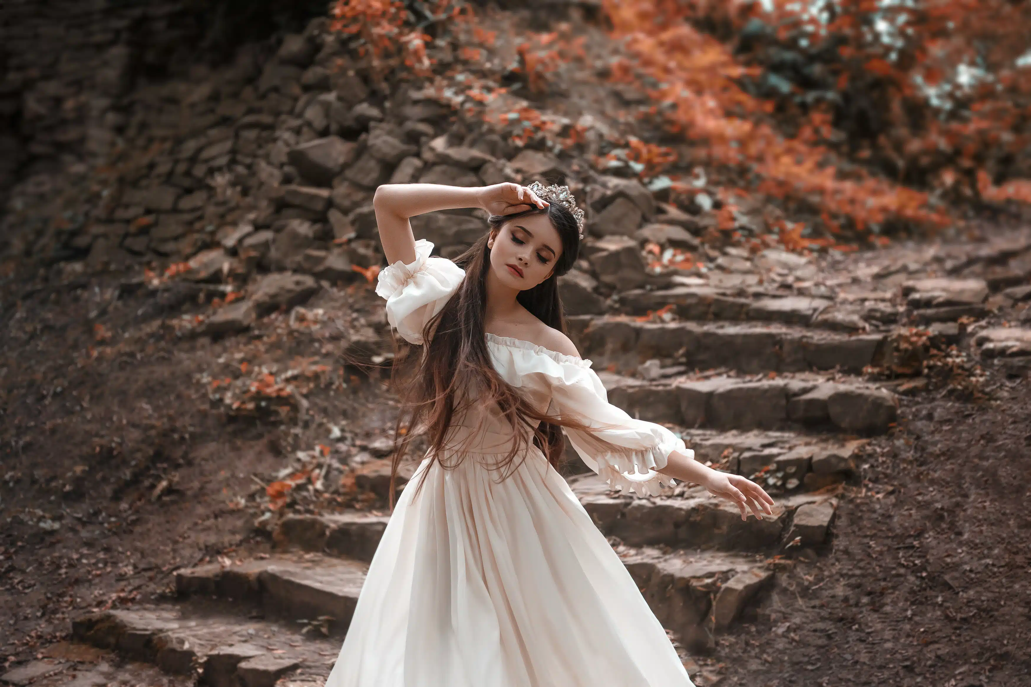 Young princess with very long hair posing against the background of an old stone staircase. 