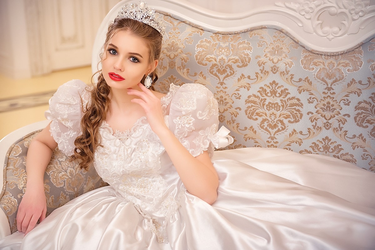 a princess wearing a tiara sitting on a vintage sofa