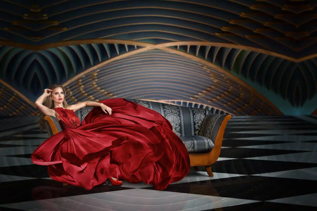 a beautiful woman dressed in luxurious red dress relaxing on a sofa