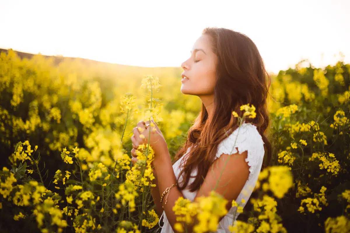 a young lady relaxing in yellow flower field at daylight