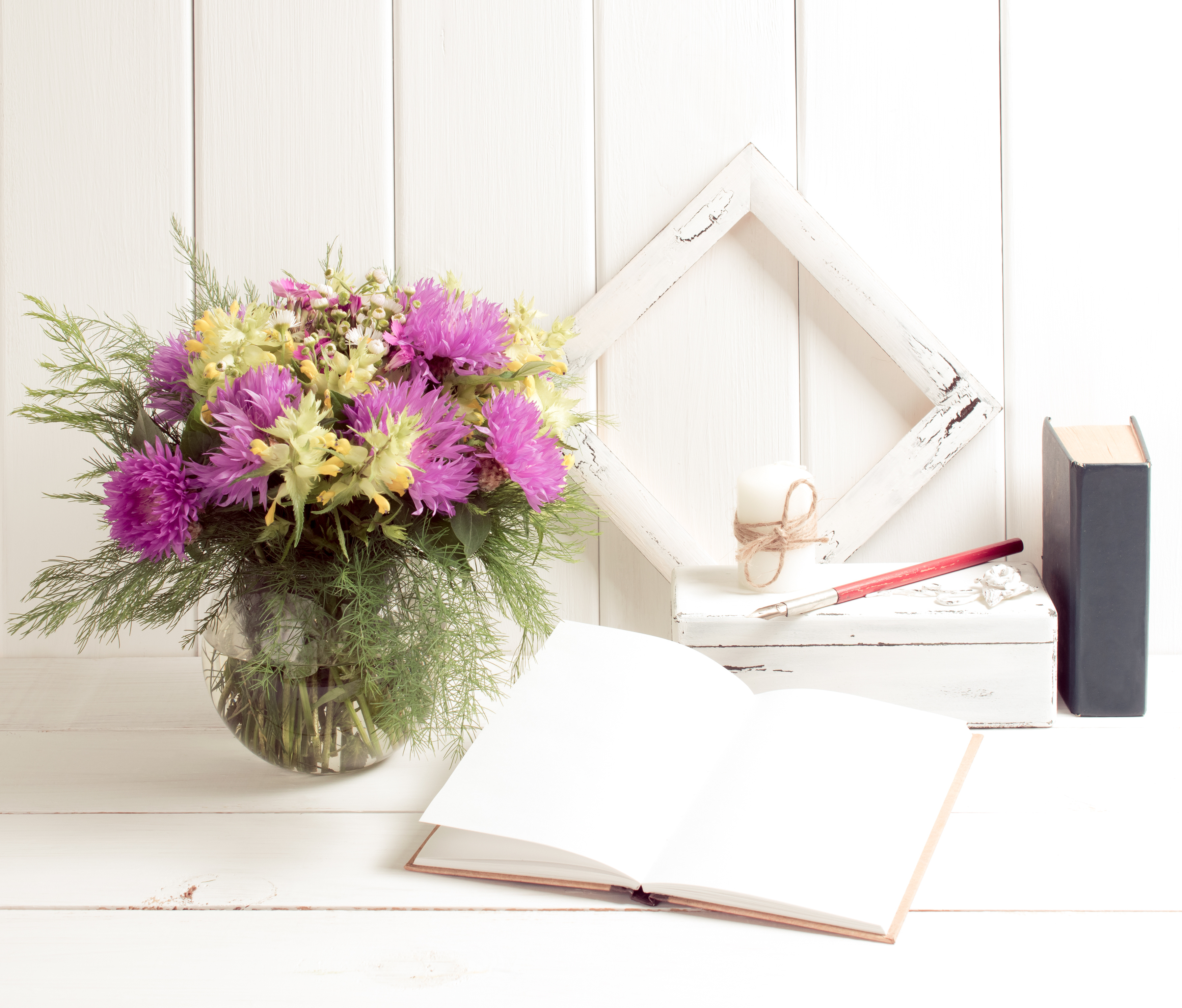 pink flowers in vase with open diary, book and frame, candle