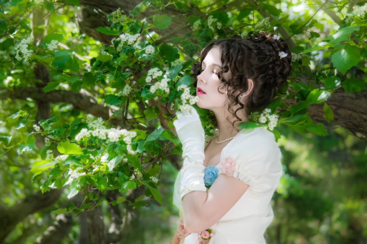 a vintage young lady in a pretty white dress relaxing in the green blooming garden