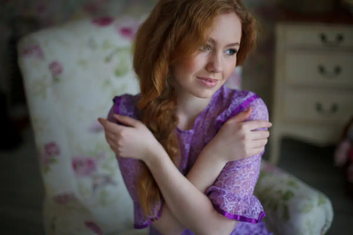 a beautiful red-haired girl in vintage dress indoors