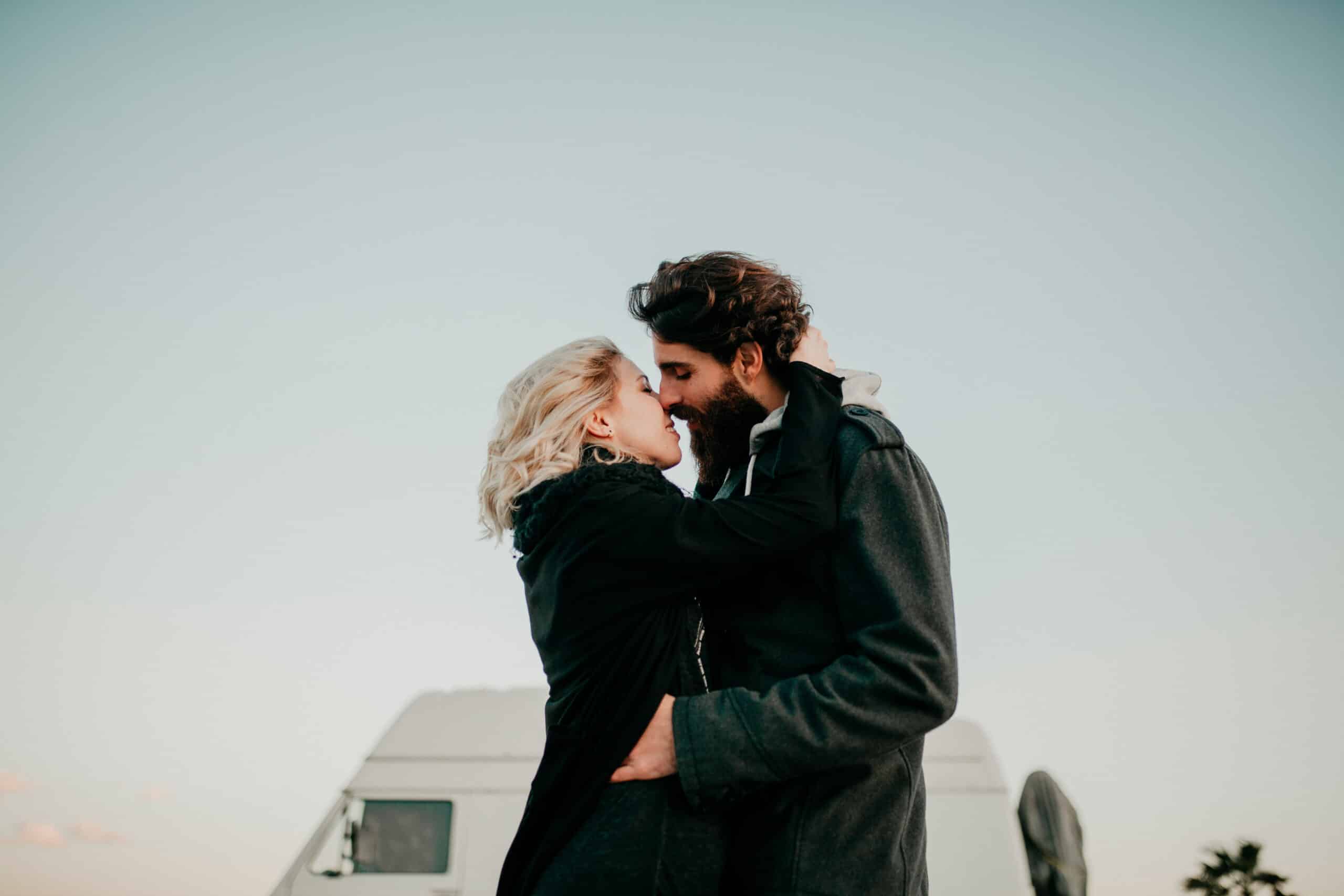 Cool young couple kissing each other outdoors while they are embracing