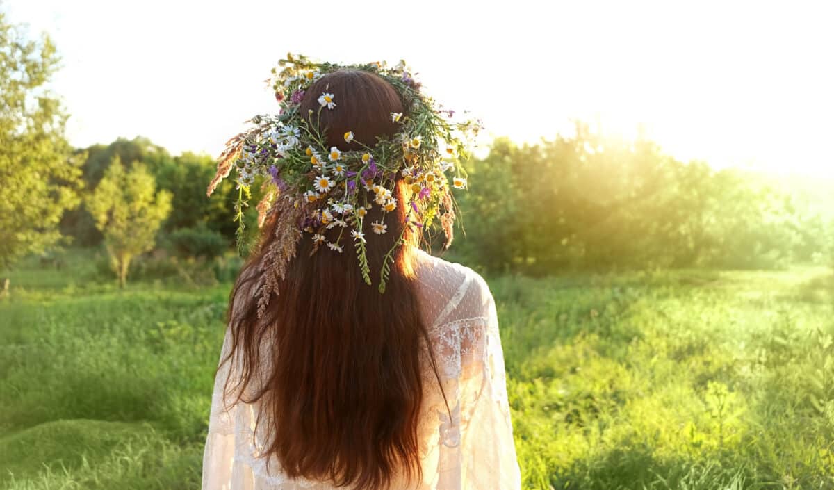 girl with flower head wreath on sunny meadow