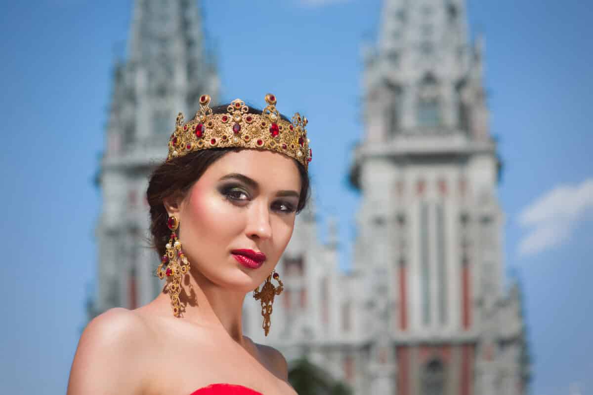 a beautiful queen in a long red dress and royal crown outdoor