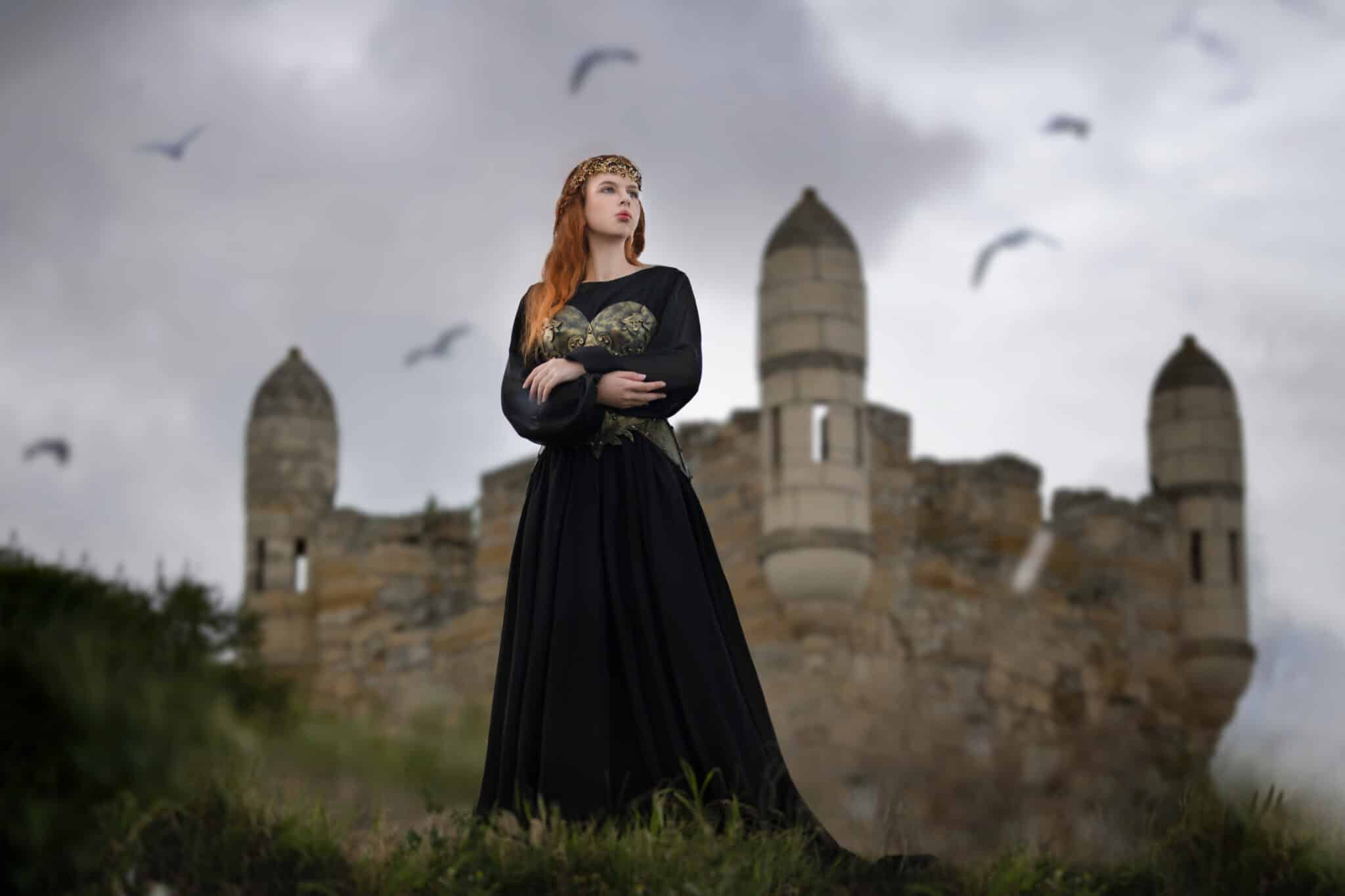 lady in a black dress standing outside the castle behind her