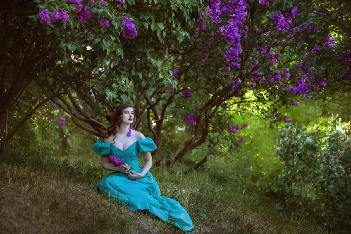 Lovely woman under a bush of lilac.
