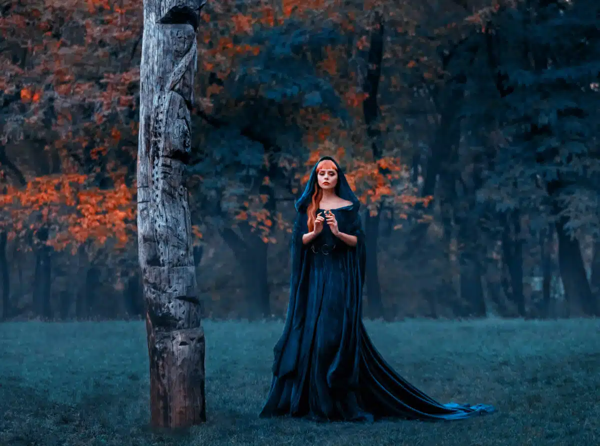 sad princess with red blond long hair dressed in green emerald expensive velvet royal cloak-dress with precious brooch, charming gorgeous girl got lost in dark foggy forest, refined pensive lady