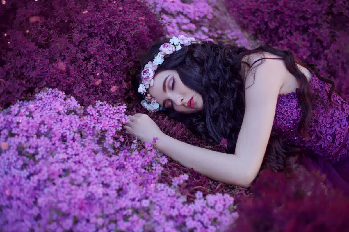 a gentle and graceful girl sleeps on a magical purple flower field, a dreaming beauty with long dark hair and a pink wreath in a purple dress, a new fairy tale about Thumbelina, bright artwork