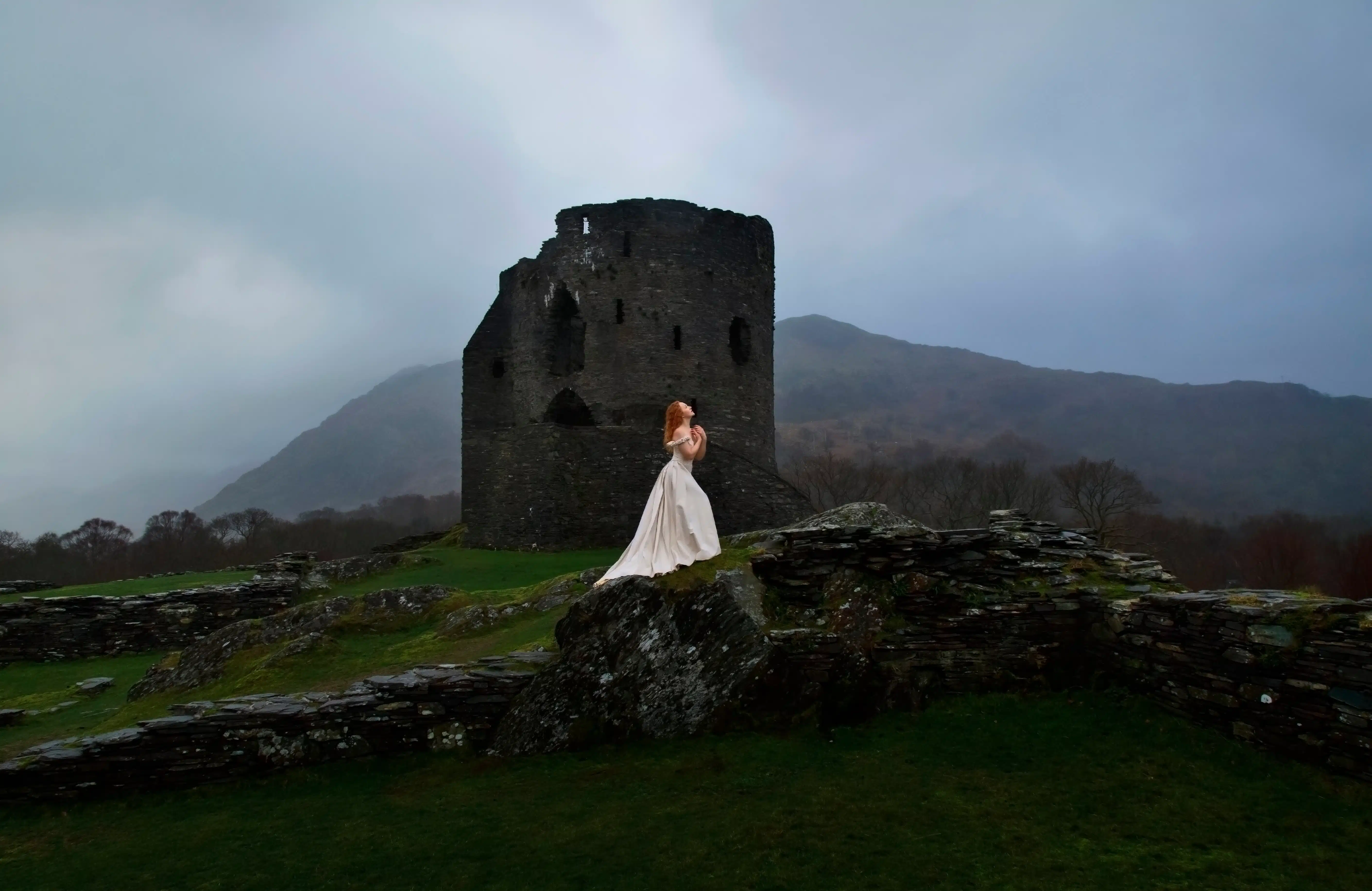Woman in long white dress standing in front of a Castle 