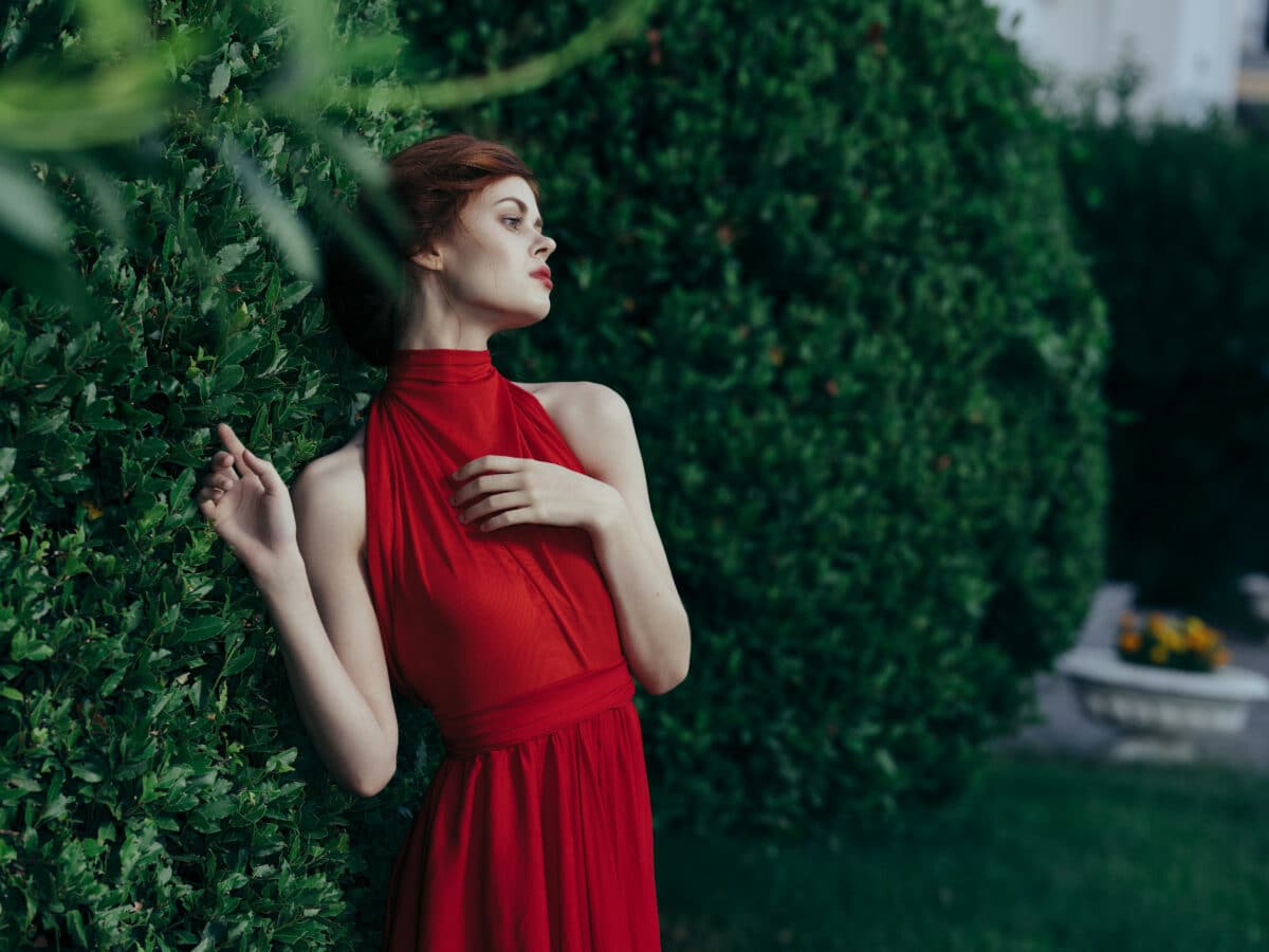 lady in red dress standing near the bush 