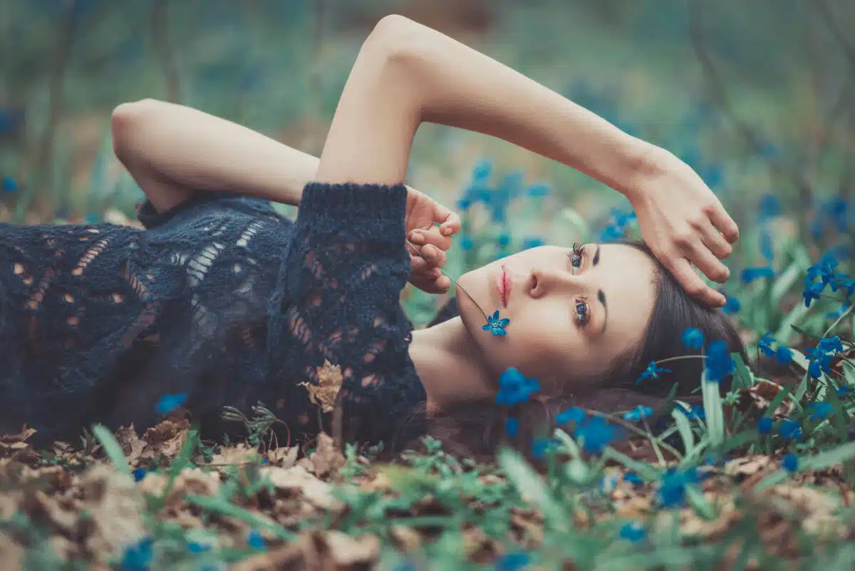 Beautiful girl lying among the snowdrops in the forest