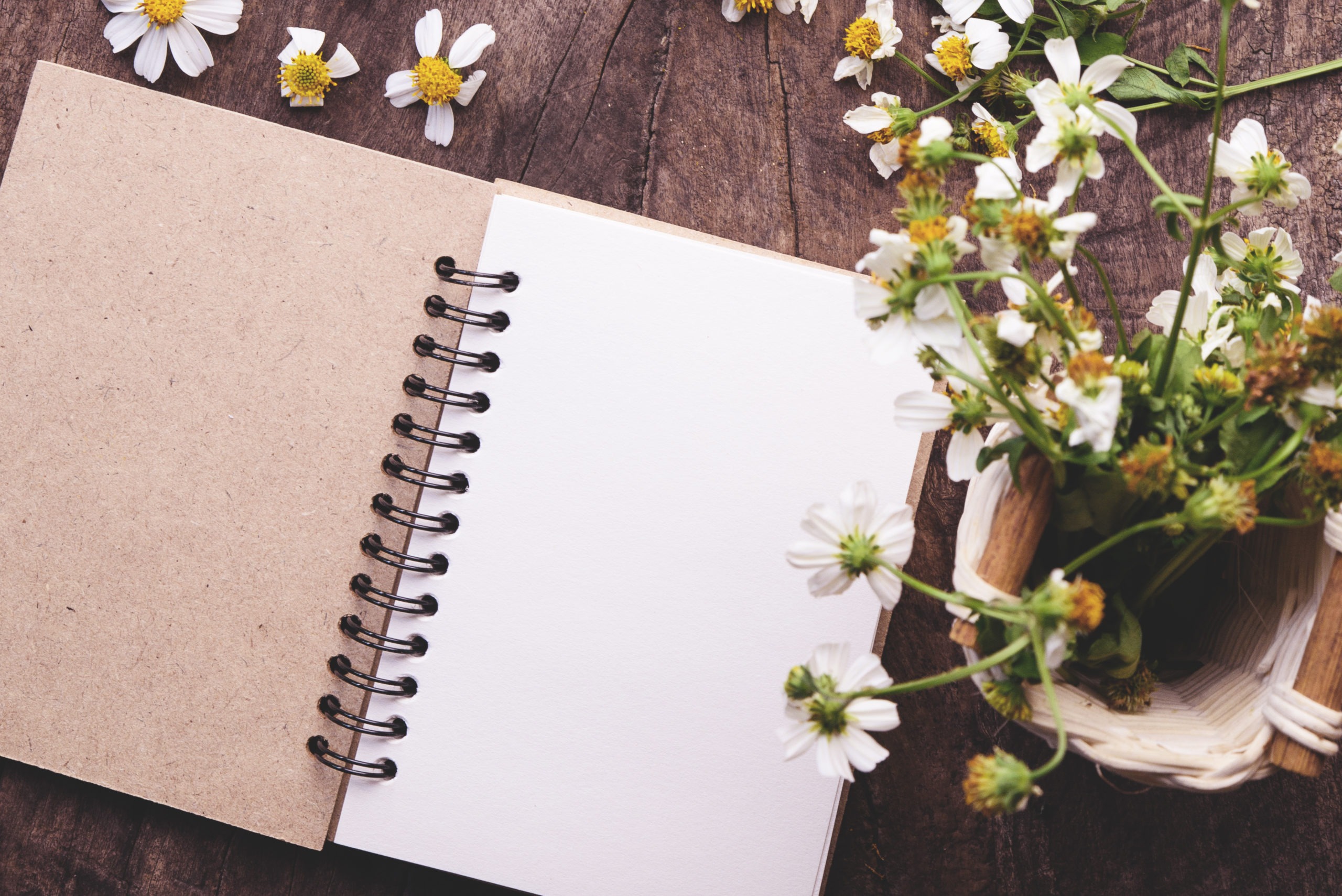 Blank notebook with white flower on vintage wooden table