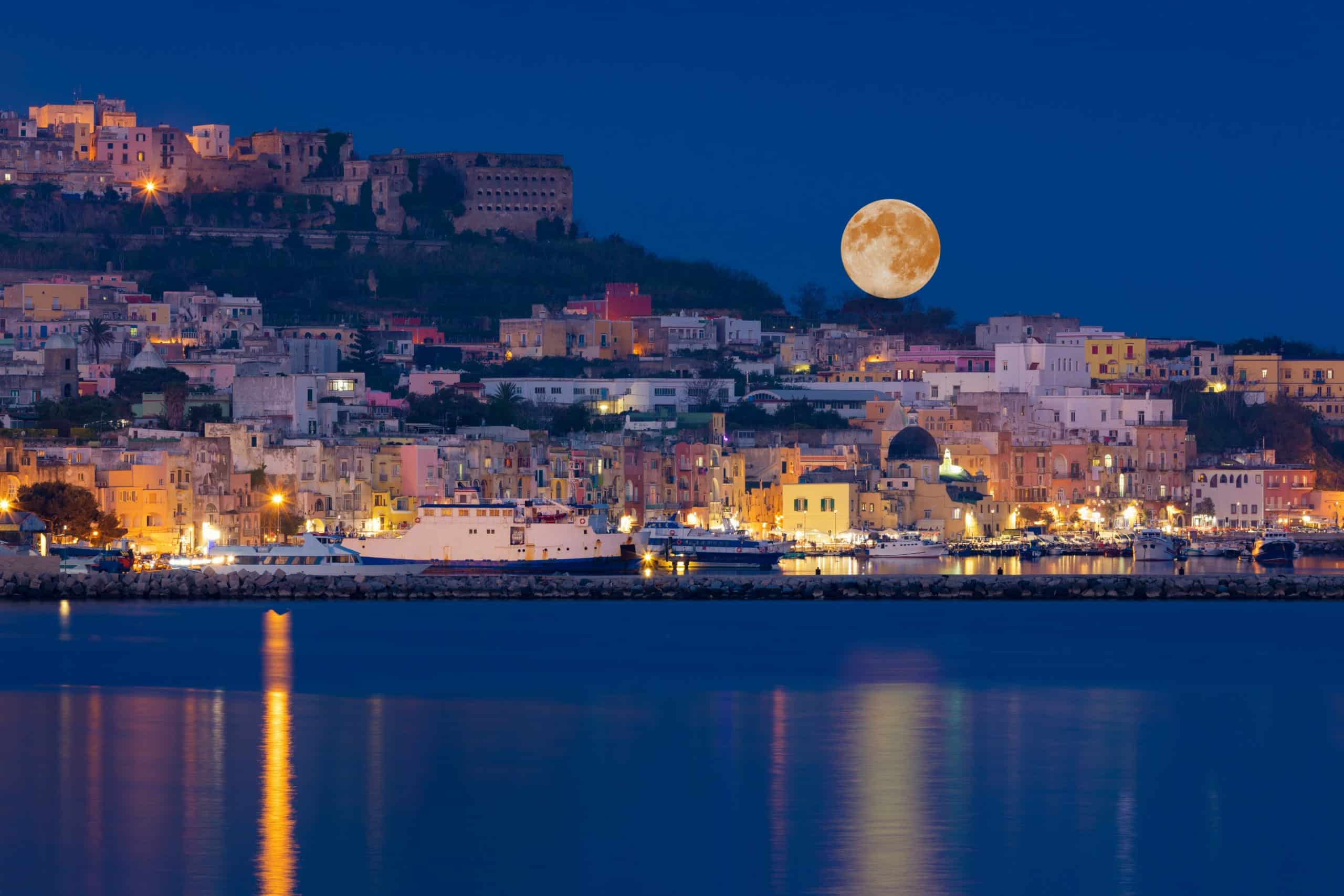 Full moon rises over coast of seaside city