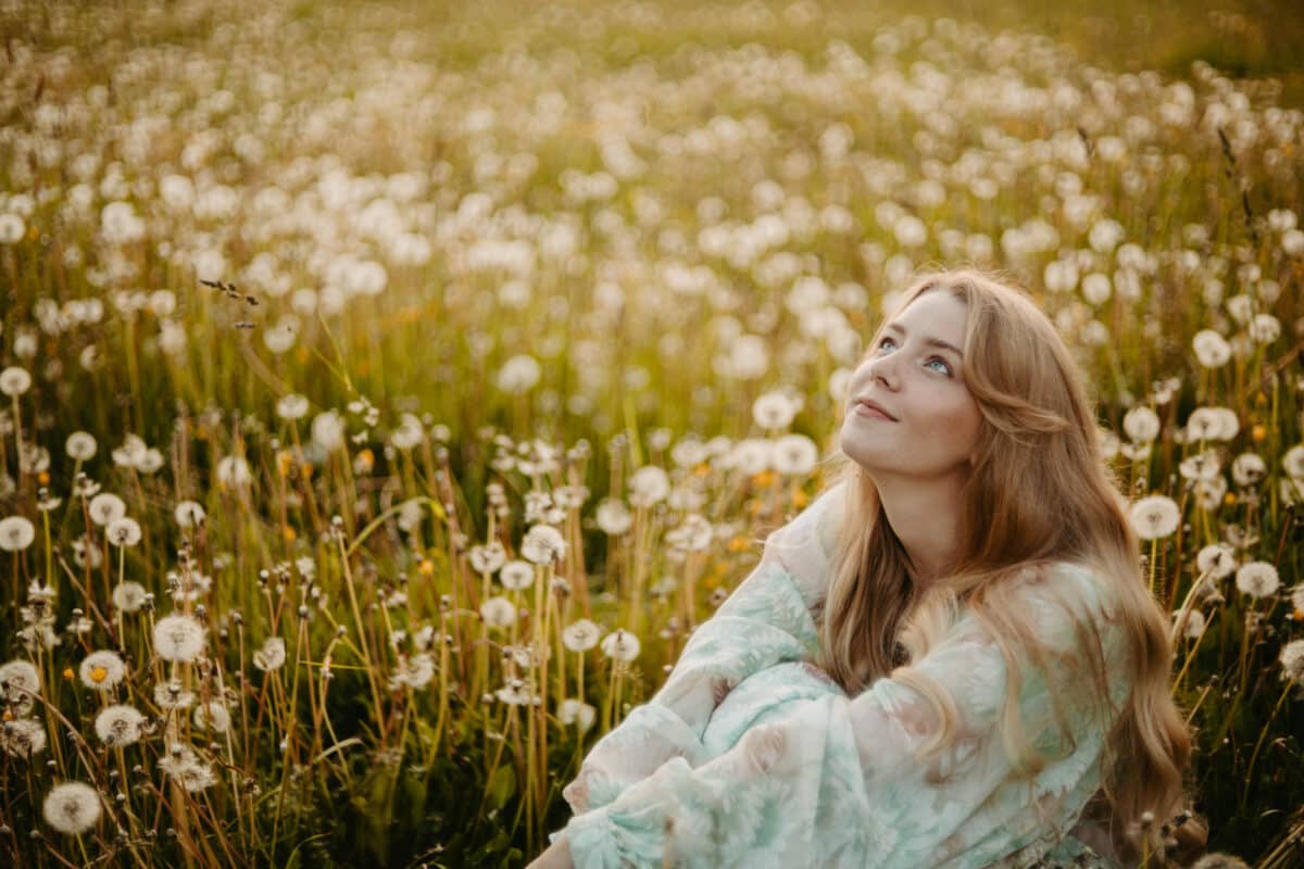 young woman in a dress in a dandelion field at sunset