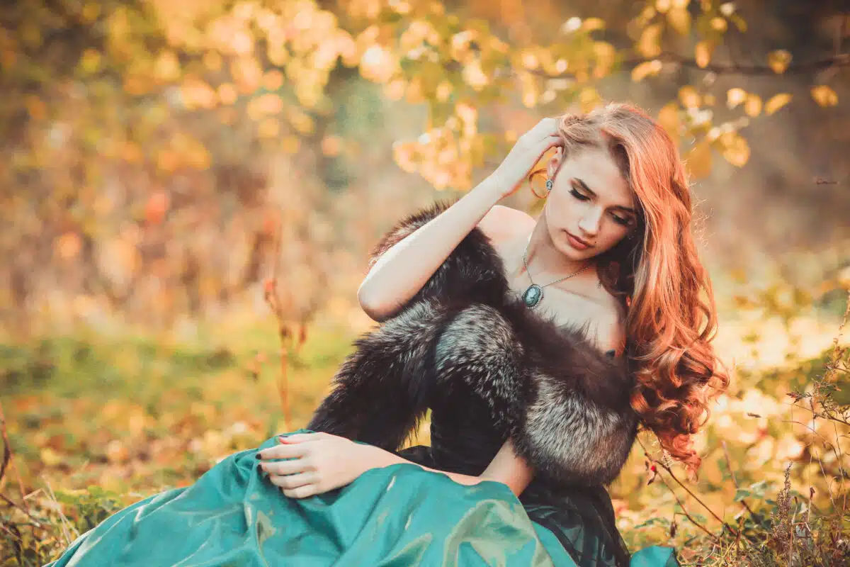 Lady in a luxury lush pastel green dress sitting in the woods