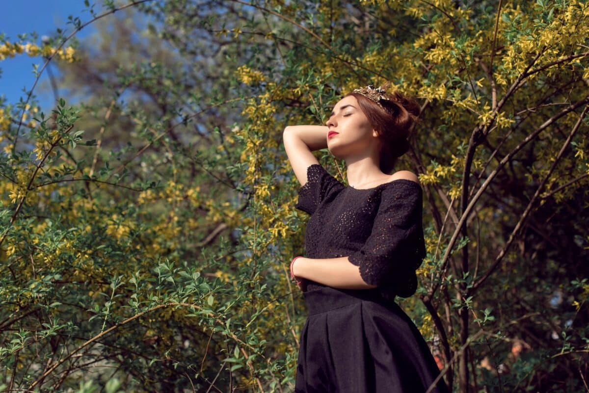 a lady in black basking in the sun in the woods