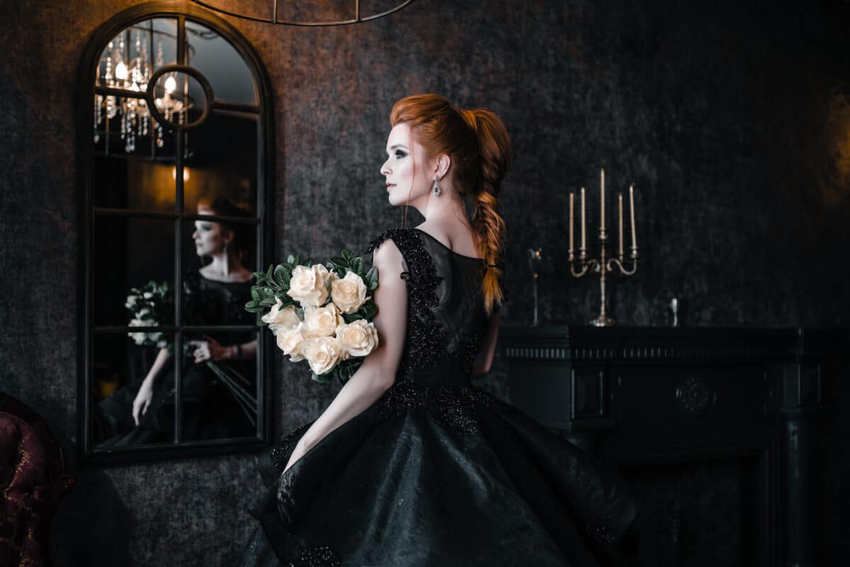 Attractive woman in gothic black dress in medieval castle