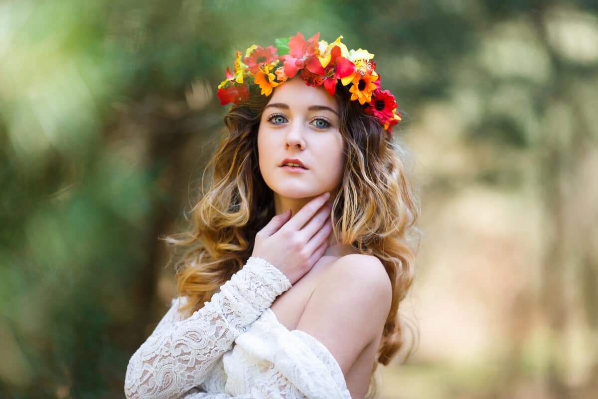 Beautiful lady with a flower head wreath in a forest